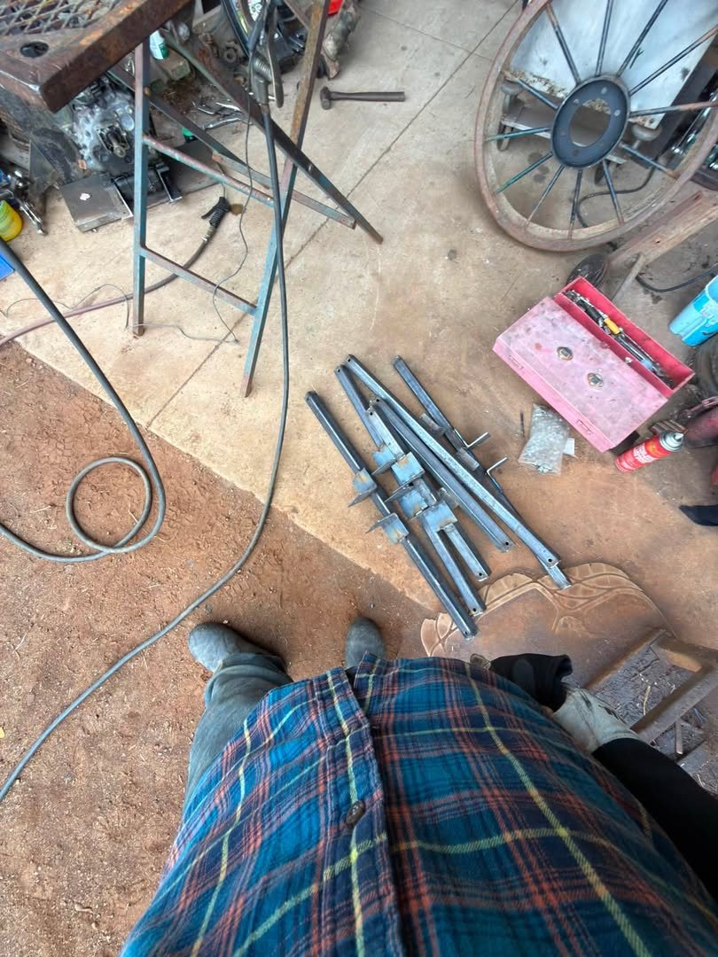 Cut steel tubing and rod laid out on the shop floor with welding leads